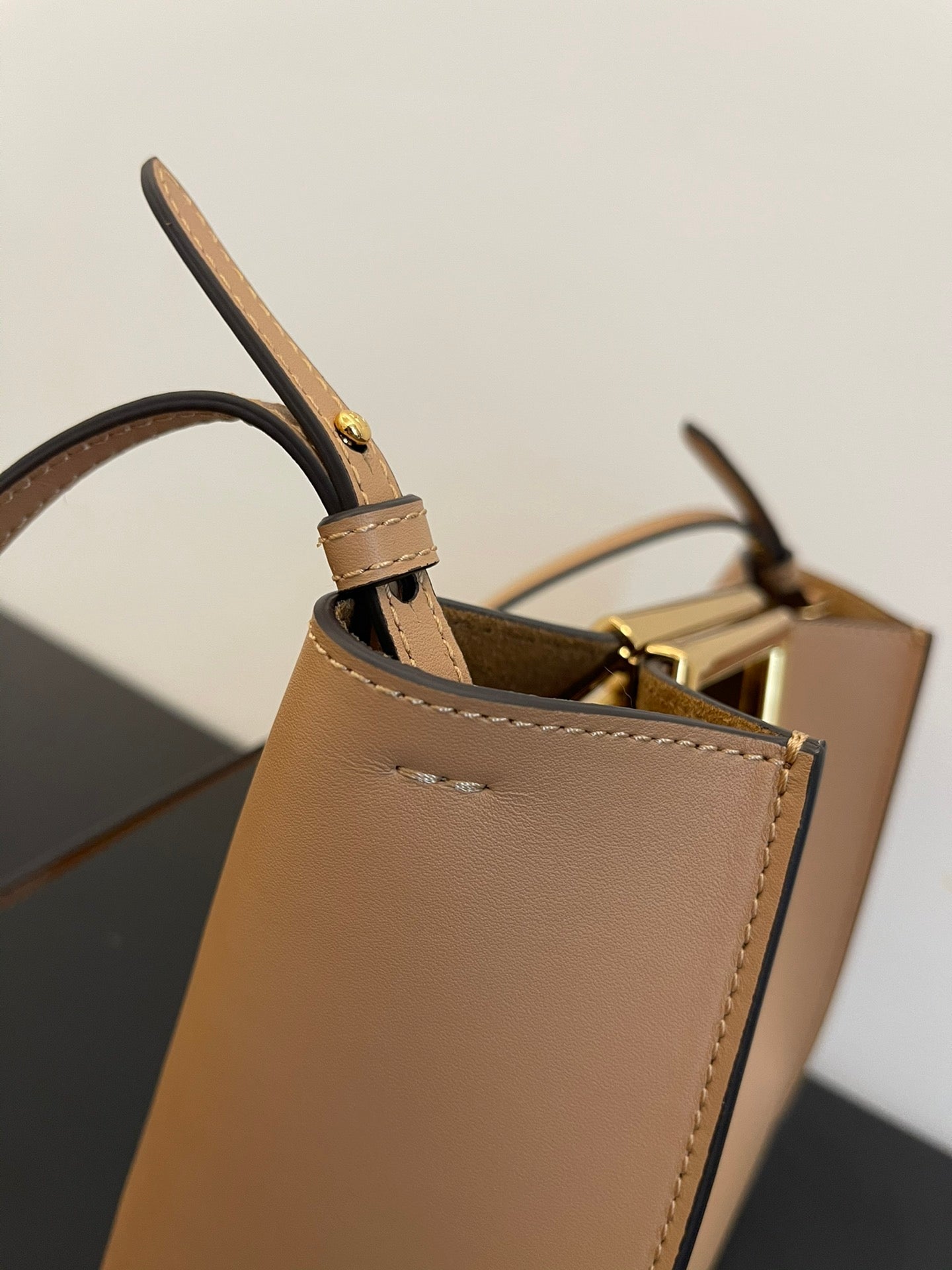 Tan Leather Bucket Bag with Gold Geometric Clasp and Shoulder Strap